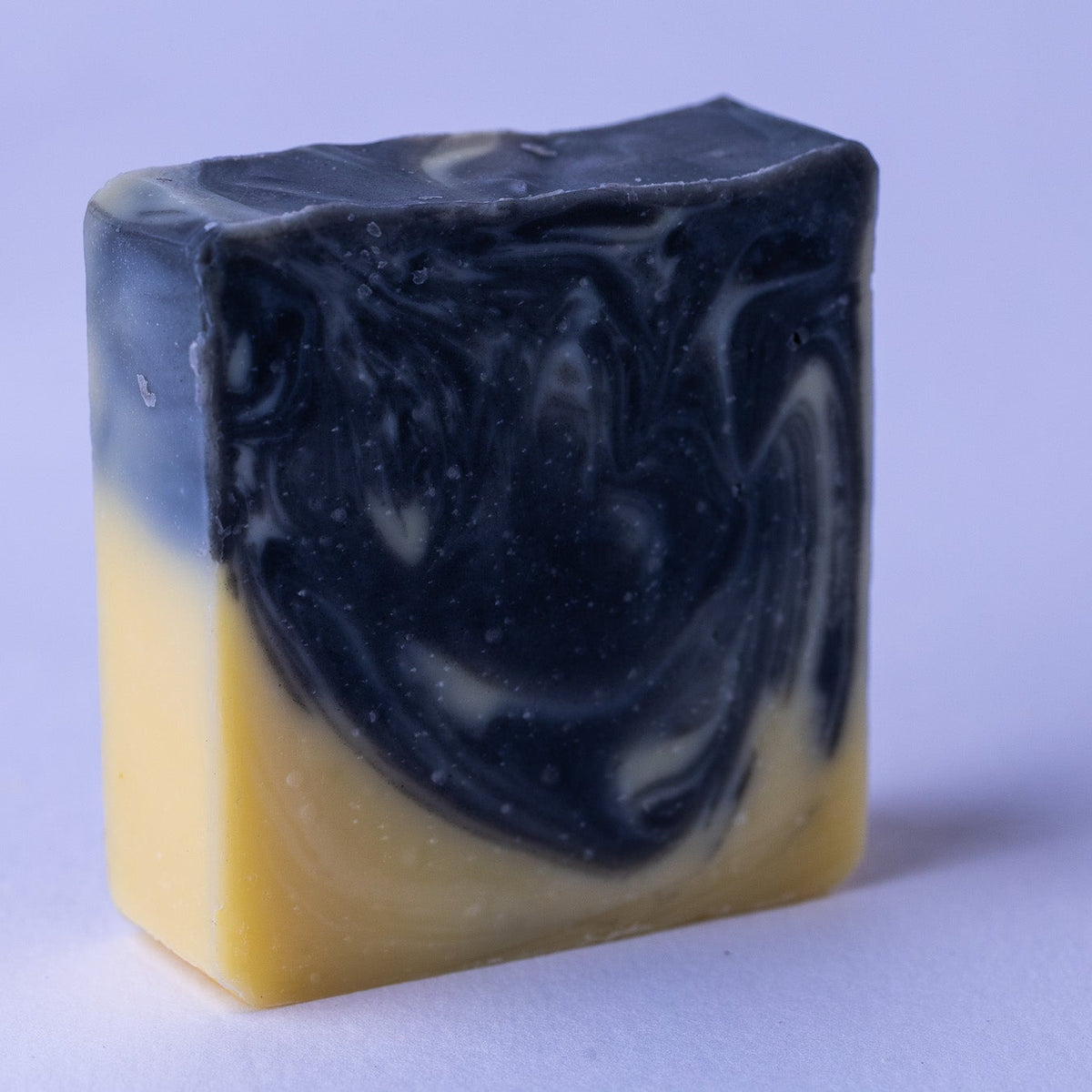 Two-tone soap bar with black and yellow colors on a light purple background