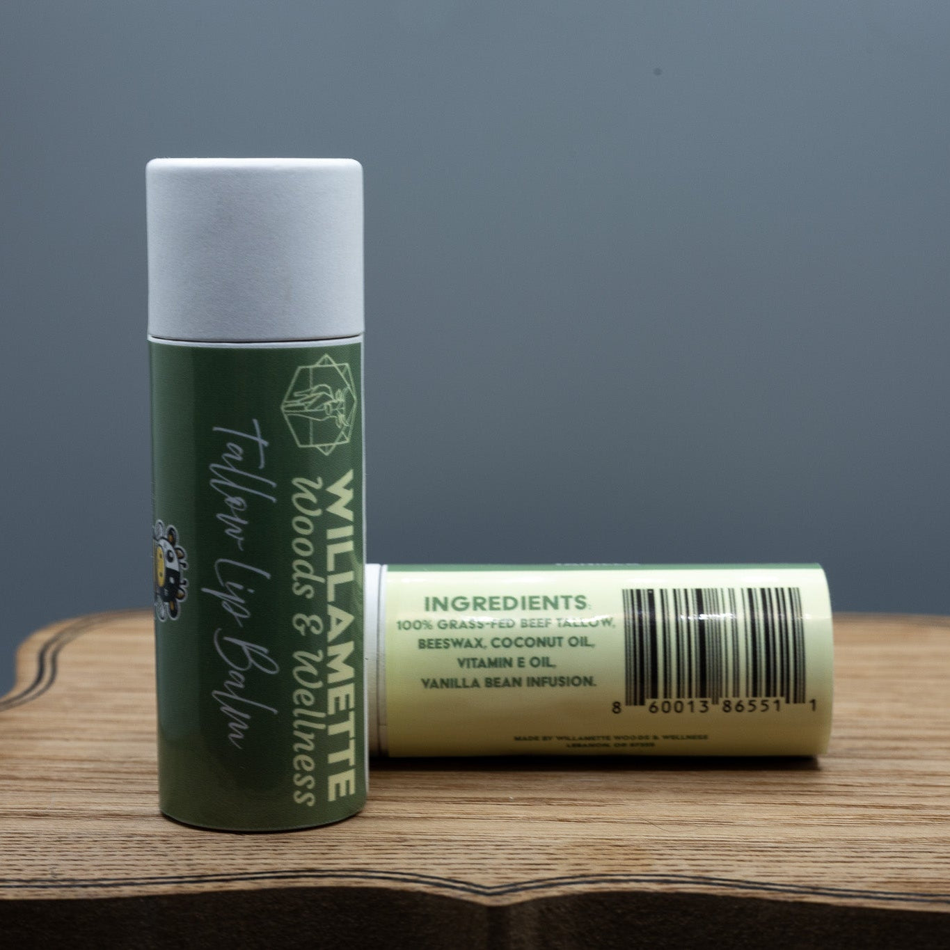 Two lip balm tubes on a wooden surface with a gray background